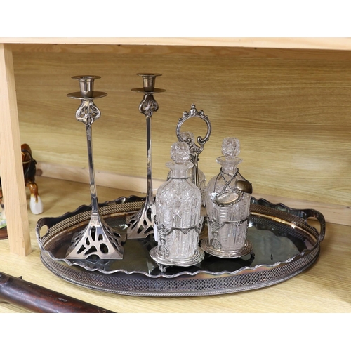 386 - An oval silver plated tray, a three bottled tantalus and a pair of candlesticks, a silver Whiskey ... 