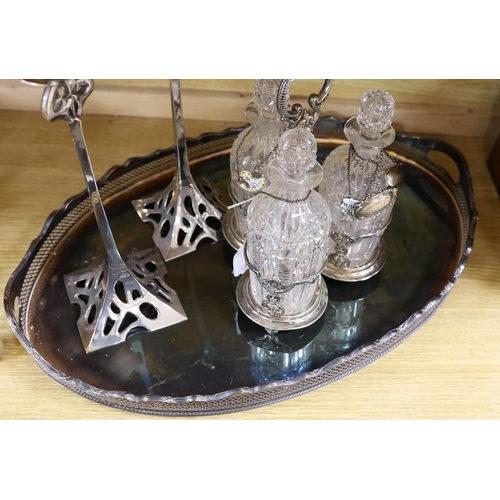 386 - An oval silver plated tray, a three bottled tantalus and a pair of candlesticks, a silver Whiskey ... 