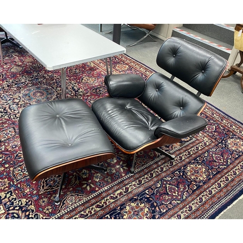 91 - A pair of Eames style black leather, simulated rosewood swivel lounge chairs and footstools