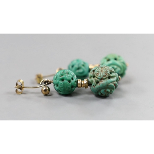 940 - A pair of Chinese yellow metal and two turquoise bead set earrings, both carved with Shou medallions... 