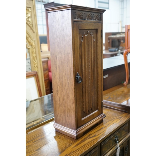 1038 - A reproduction 18th century style carved and linen fold moulded oak side cabinet and matching media ... 