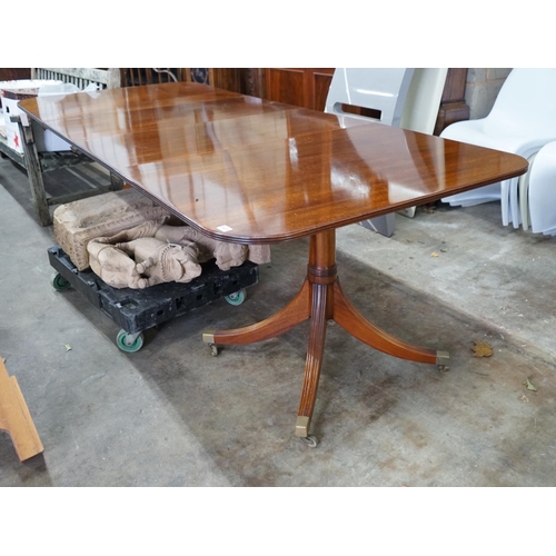 1073 - A reproduction Tillman style mahogany twin pillar extending dining table 246cms extended, two spare ... 