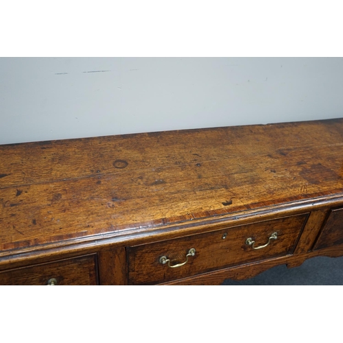 1163 - A George III provincial oak and mahogany banded low dresser with three drawers on square tapering le... 