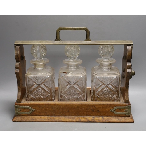 1263 - A Victorian Betjemanns patent oak cased three bottle tantalus (a.f.), 42cms wide at base