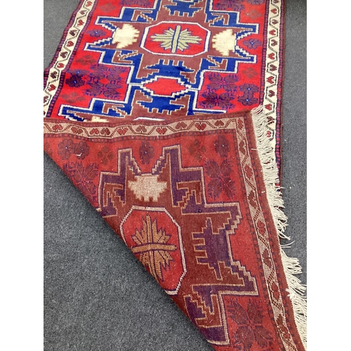 140 - A Caucasian style red ground triple medallion rug, 180 x 98cm