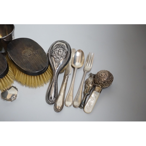 806 - A mixed group of silverware including a pair of silver mounted clothes brushes, two rattles, a napki... 