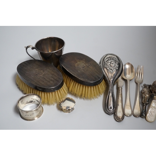 806 - A mixed group of silverware including a pair of silver mounted clothes brushes, two rattles, a napki... 