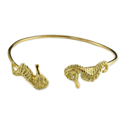 876 - A modern gold and diamond chip set open work bangle, each terminal modelled as a seahorse with diamo... 