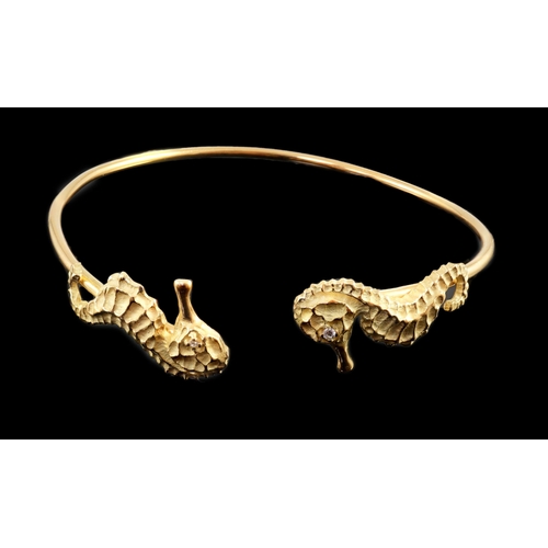 876 - A modern gold and diamond chip set open work bangle, each terminal modelled as a seahorse with diamo... 