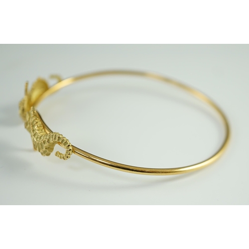 876 - A modern gold and diamond chip set open work bangle, each terminal modelled as a seahorse with diamo... 