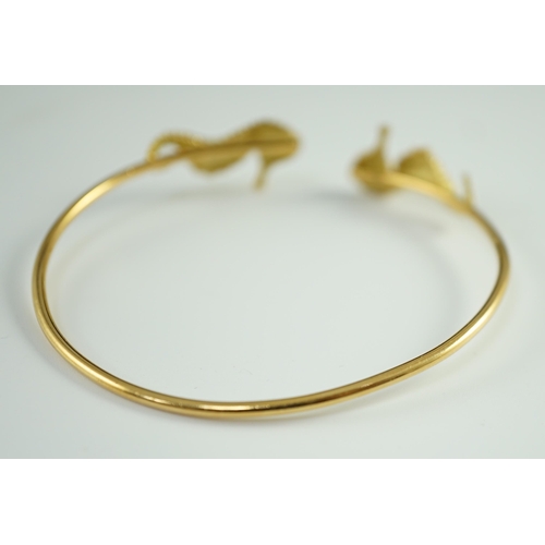 876 - A modern gold and diamond chip set open work bangle, each terminal modelled as a seahorse with diamo... 