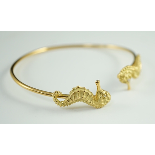 876 - A modern gold and diamond chip set open work bangle, each terminal modelled as a seahorse with diamo... 