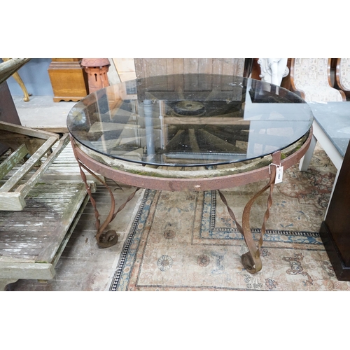 1068 - A wrought iron glass topped circular cartwheel garden table, diameter 124cm, height 72cm