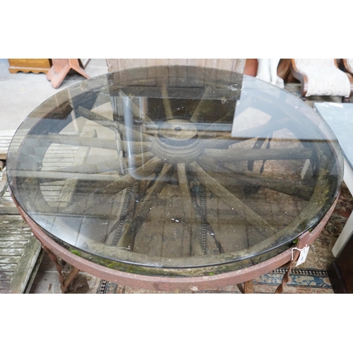 1068 - A wrought iron glass topped circular cartwheel garden table, diameter 124cm, height 72cm