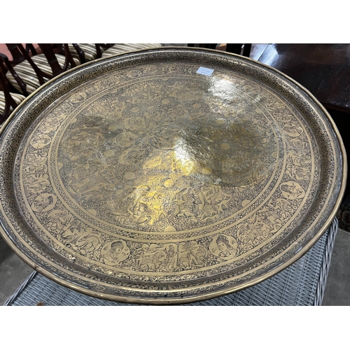 1057 - A Benares engraved brass circular tray top table on folding stand, diameter 67cm, height 59cm