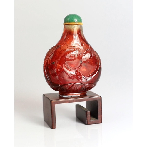 182 - A Chinese ruby red glass leaping carp snuff bottle, 1750-1850, each side carved in high relief wit... 