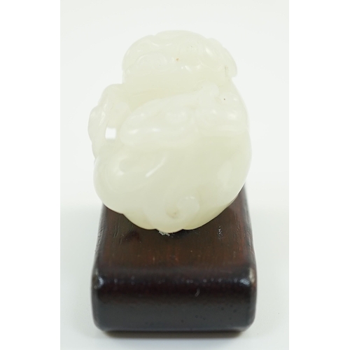 219 - A Chinese white jade figure of a pug dog, 19th/20th century, the dog biting a sprig of lingzhi fungu... 