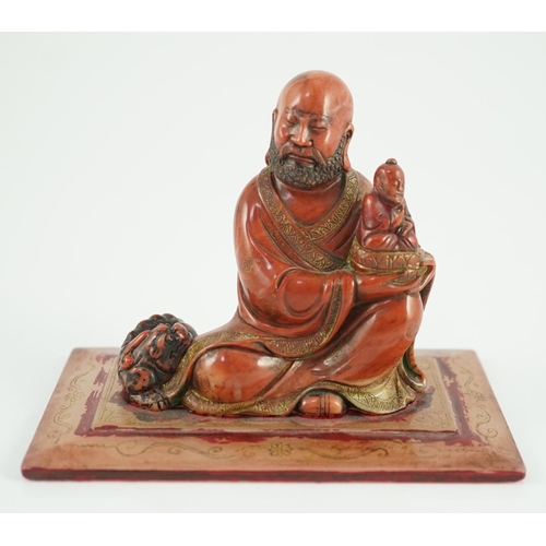 224 - A Chinese soapstone group of a luohan holding a figure of Buddha, 18th century, wearing flowing robe... 