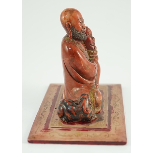 224 - A Chinese soapstone group of a luohan holding a figure of Buddha, 18th century, wearing flowing robe... 