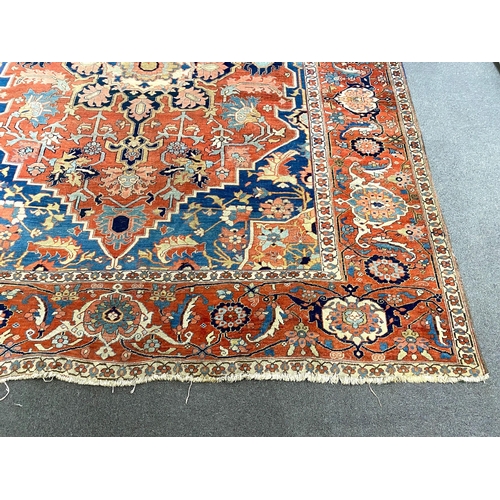 250 - An antique Heriz brick red ground carpet, with large central floral medallion within a wide conformi... 