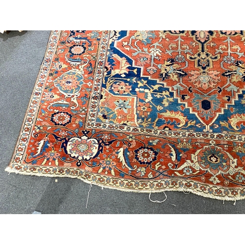 250 - An antique Heriz brick red ground carpet, with large central floral medallion within a wide conformi... 