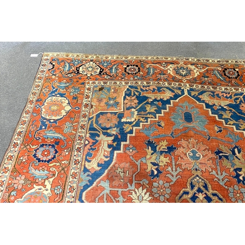 250 - An antique Heriz brick red ground carpet, with large central floral medallion within a wide conformi... 