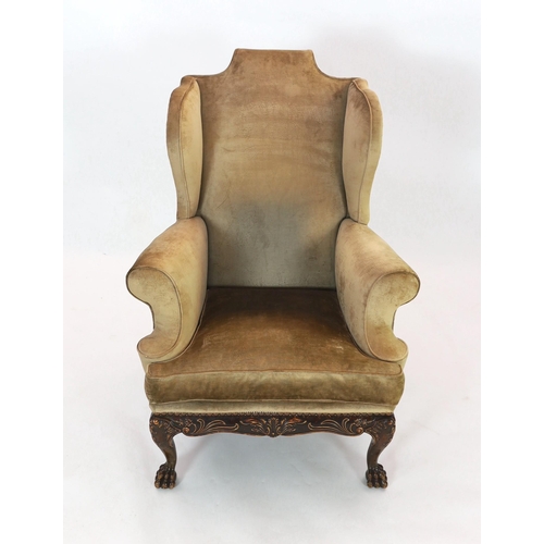 270 - An Irish mahogany wing armchair, in George III style, with foliate scroll carved apron, on cabriole ... 