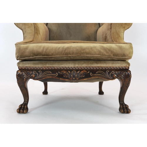 270 - An Irish mahogany wing armchair, in George III style, with foliate scroll carved apron, on cabriole ... 