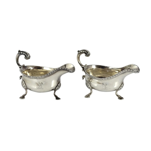 434 - A near pair of George III silver sauceboats, with gadrooned borders, engraved crest and flying scrol... 