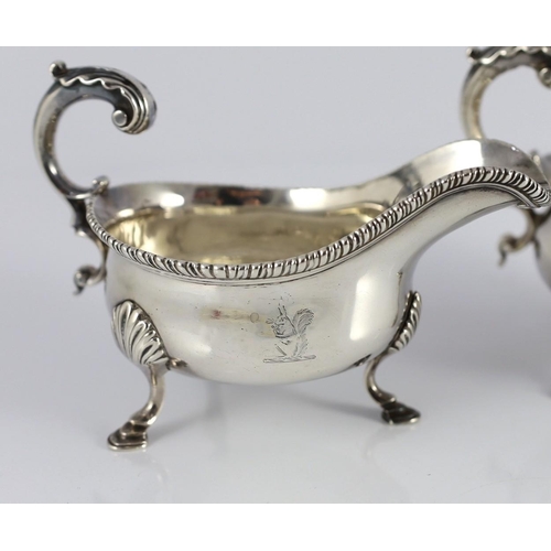 434 - A near pair of George III silver sauceboats, with gadrooned borders, engraved crest and flying scrol... 