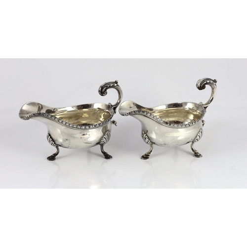 434 - A near pair of George III silver sauceboats, with gadrooned borders, engraved crest and flying scrol... 