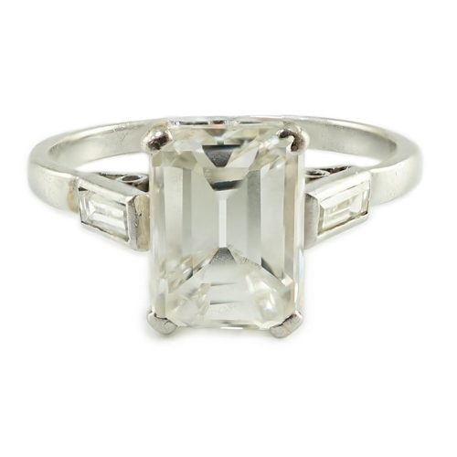 541 - A platinum and single stone emerald cut diamond set ring, with baguette cut diamond set shoulders, t... 