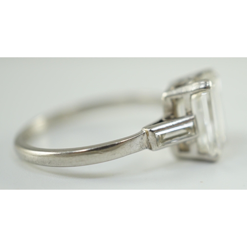 541 - A platinum and single stone emerald cut diamond set ring, with baguette cut diamond set shoulders, t... 