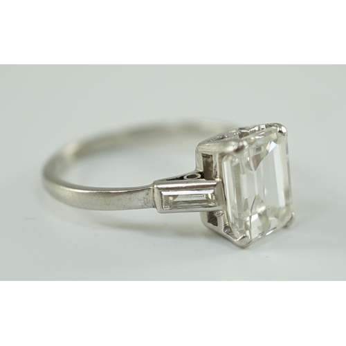 541 - A platinum and single stone emerald cut diamond set ring, with baguette cut diamond set shoulders, t... 