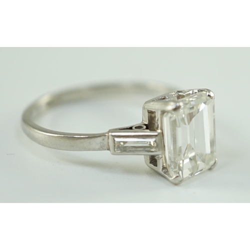 541 - A platinum and single stone emerald cut diamond set ring, with baguette cut diamond set shoulders, t... 