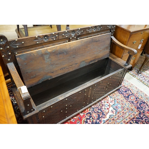 1124 - An 18th century style brass studded carved oak box seat settle, length 136cm, depth 40cm, height 93c... 