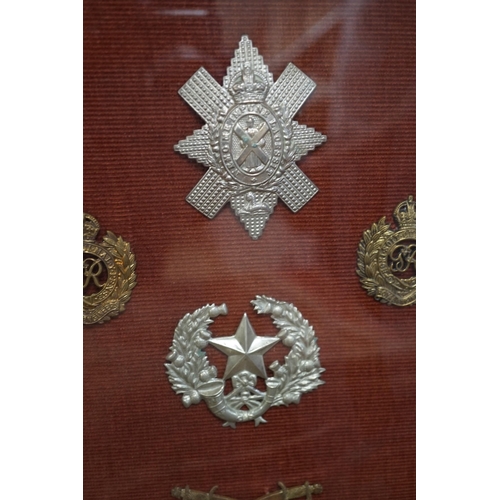 1452 - A framed collection of military cap Badges