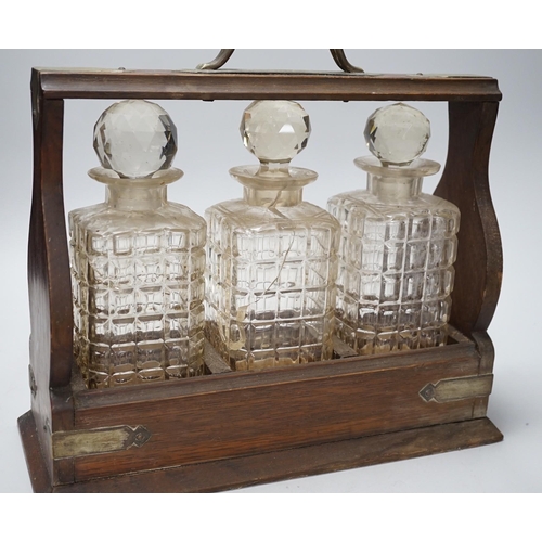 272 - A three bottle oak and electroplate mounted tantalus, 36cms x 33cms high