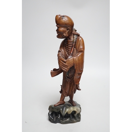 457 - An early 20th century Chinese hardwood carving of a luohan, on soapstone base, 36cm tall