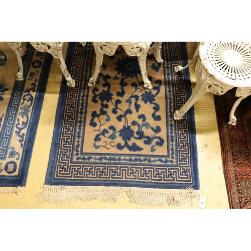 95 - A pair of Chinese beige ground rugs and a similar rug, 174 x 92cm