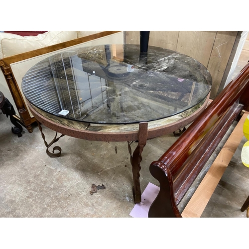 1106 - A wrought iron glass topped circular cartwheel garden table, diameter 124cm, height 72cm