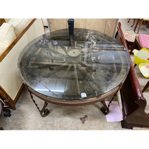 1106 - A wrought iron glass topped circular cartwheel garden table, diameter 124cm, height 72cm