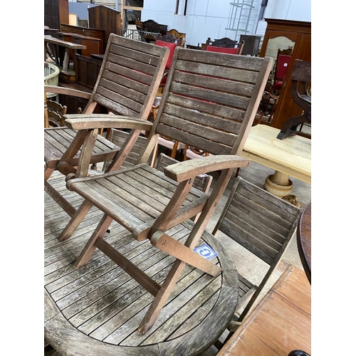 1175 - A weathered teak folding oval garden table, length 150cm, depth 91cm, height 74cm together with eigh... 