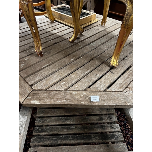 111 - An octagonal weathered teak garden table, length 126cm, height 69cm and four teak elbow chairs... 