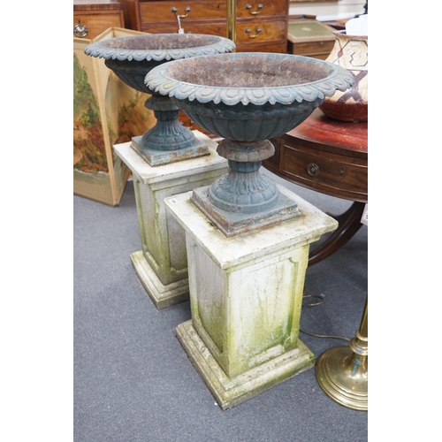 189 - A pair of Victorian painted cast iron campana garden urns on square stone plinths, diameter 51cm, he... 