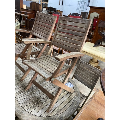 243 - A weathered teak folding oval garden table, length 150cm, depth 91cm, height 74cm together with eigh... 