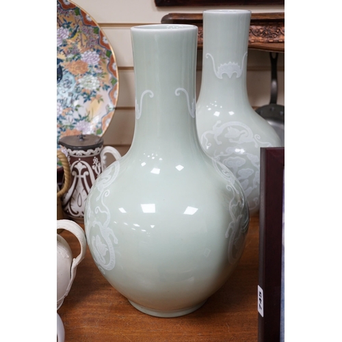 618A - A pair of Chinese white slip decorated celadon glazed bottle vases, mid 20th century, 39cm