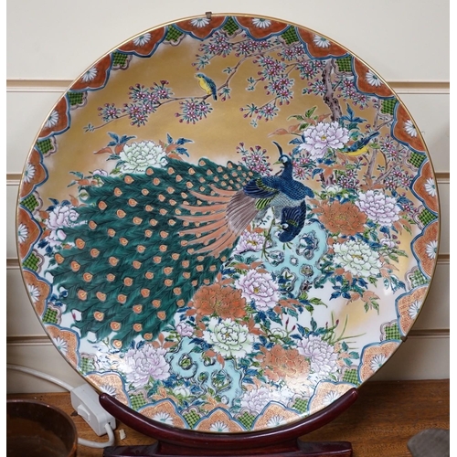 619 - A Japanese enamelled porcelain peacock dish on hardwood stand, dish 41cm diameter