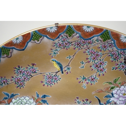 619 - A Japanese enamelled porcelain peacock dish on hardwood stand, dish 41cm diameter