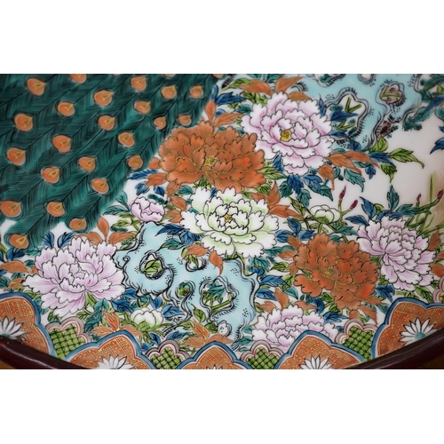 619 - A Japanese enamelled porcelain peacock dish on hardwood stand, dish 41cm diameter